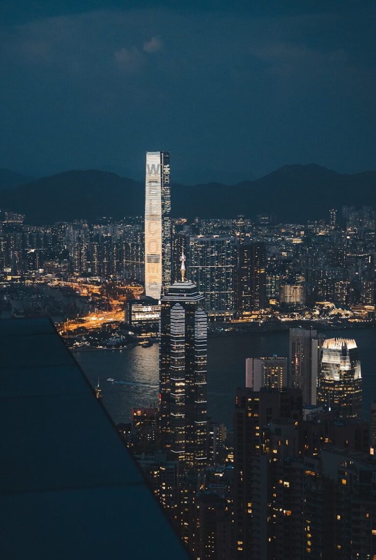 Modern skyscrapers illuminated at night overlooking a bay.